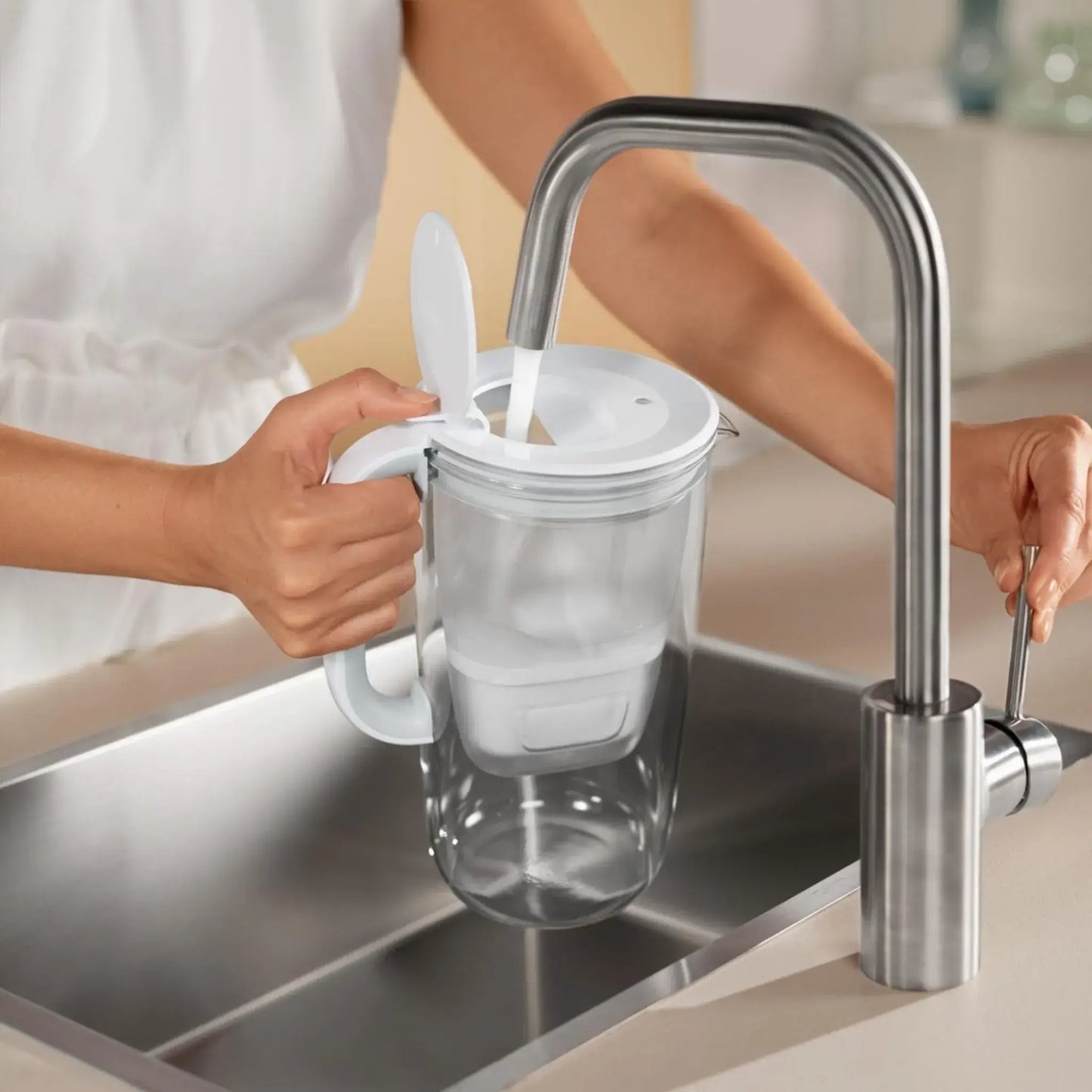 Person fyller Brita vattenfilterkanna i glas 2.5L med vatten direkt från kran.