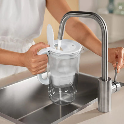 Person fyller Brita vattenfilterkanna i glas 2.5L med vatten direkt från kran.